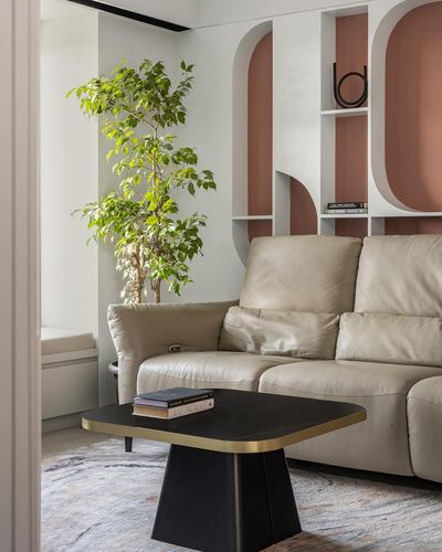 Beige leather sofa beside a black and gold coffee table with terracotta arched wall niches