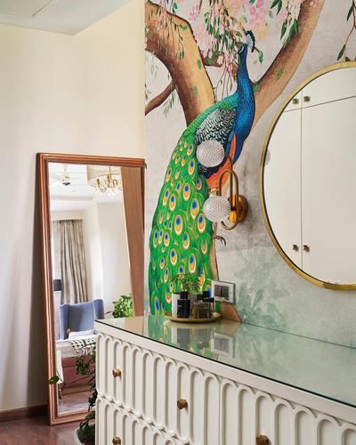 Foyer with peacock mural, round gold mirror, and fluted white console table