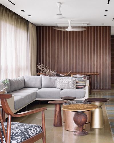 Living room with fluted wood wall, grey sectional sofa, and cluster of round metallic side tables
