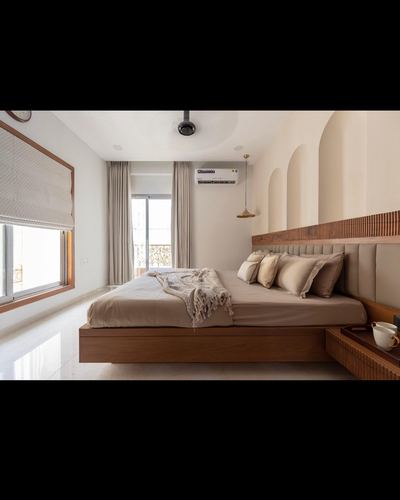 Warm-toned bedroom with floating wood bed, ribbed headboard, and arched wall niches beside a window