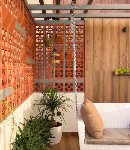 Balcony with terracotta jali screen wall, wooden wall, hanging swing, and potted plants