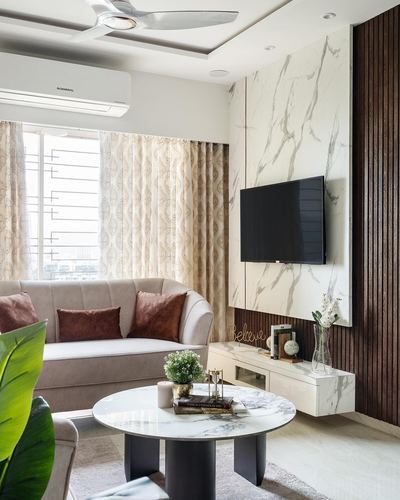 Living room with marble-look tv panel, fluted wood wall, beige sofa and round marble coffee table