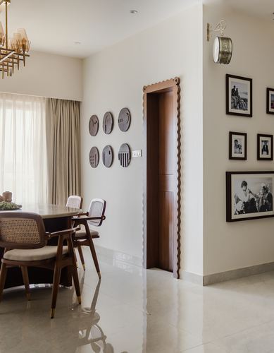 Dining nook beside a scalloped wooden door frame and black-and-white photo gallery wall