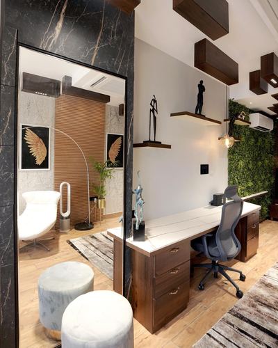 Home study with wooden desk, floating shelves, marble stools, and mirror reflecting a floral accent wall