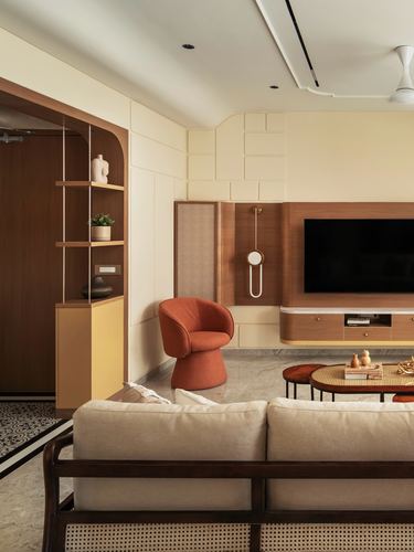 Living room with wood tv unit, orange bouclé chair, cane stools, and marble floor