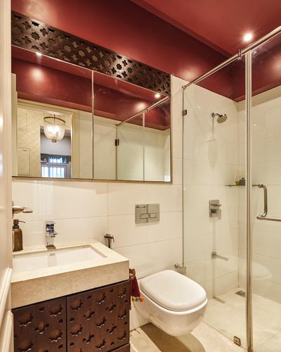 Bathroom with maroon ceiling, carved wood mirror frame, marble vanity, glass shower enclosure