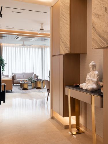 Entry foyer with marble-clad wall niche, brass-legged console and Buddha statue beside living room view