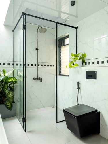 White marble bathroom with black-framed glass shower enclosure and black wall-hung toilet