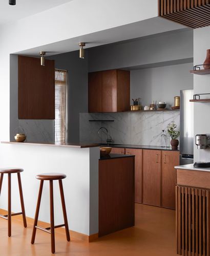 Warm wood kitchen with marble backsplash, terracotta flooring, and two turned wood bar stools