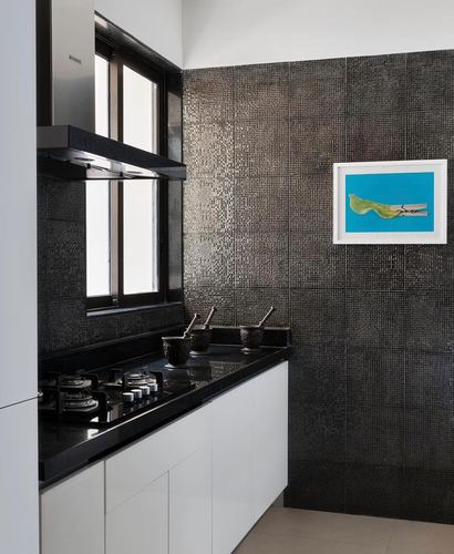 Black textured tile kitchen wall with white cabinetry, black countertop, and framed art