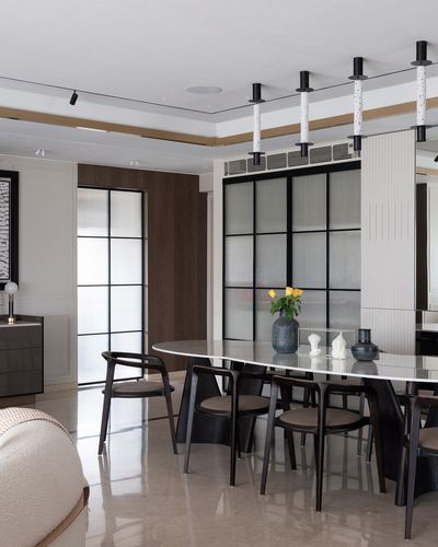 Dining room with oval stone table, dark wood chairs, and black-framed glass partition