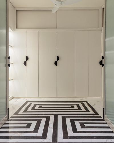 Symmetrical foyer with glossy white wardrobe wall and black-white geometric marble floor pattern