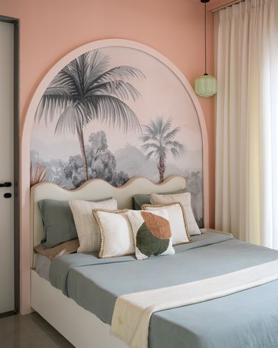 Bed with scalloped headboard beneath an arched palm tree mural on pink wall