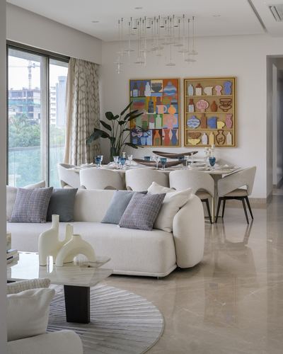 Open living and dining space with boucle sofa, marble floor, and colorful framed vase artwork