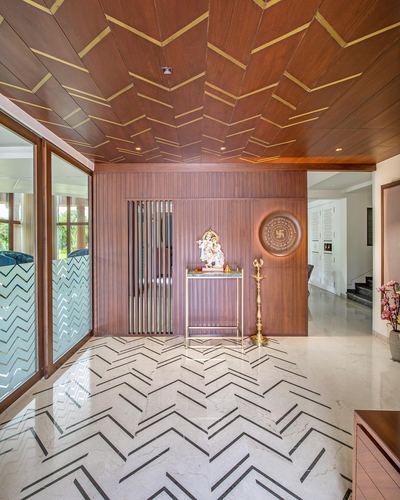 Wood-panelled foyer with chevron ceiling, marble chevron floor, and a small pooja console with Ganesh idol.