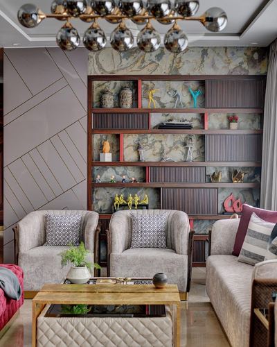Living room with grooved wood shelving, stone backdrop, and cluster of curios beside grey armchairs