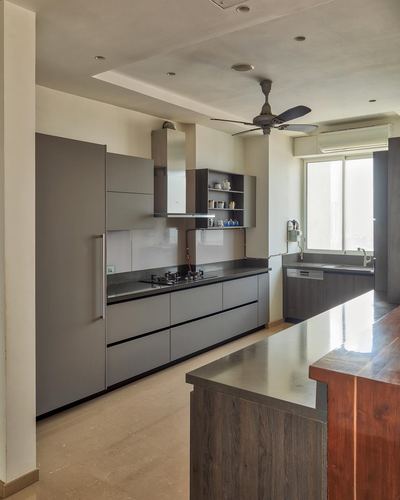 Minimalist grey modular kitchen with wood-topped island and city view window