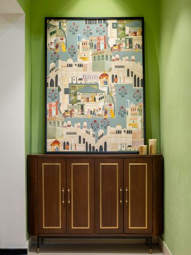 Wooden sideboard with brass trim below a framed Indian miniature-style painting in a green wall niche