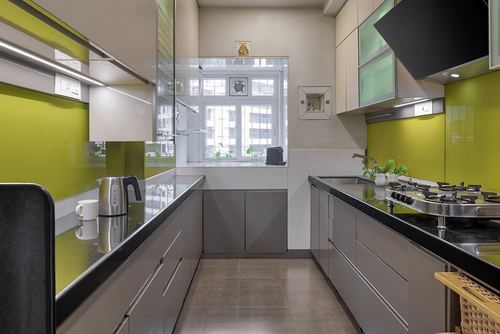 Parallel galley kitchen with olive-green glossy backsplash, grey glossy cabinetry and black countertops, window at far end