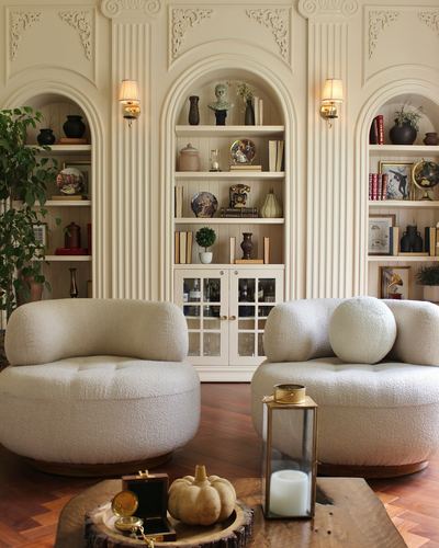 Cream living room with arched bookshelves, fluted paneling, and boucle swivel chairs on herringbone floor