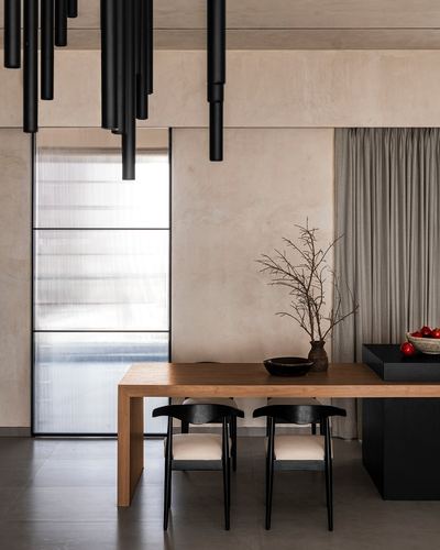 Minimalist dining area with black pendant cluster, wood table, black chairs, and fluted glass door