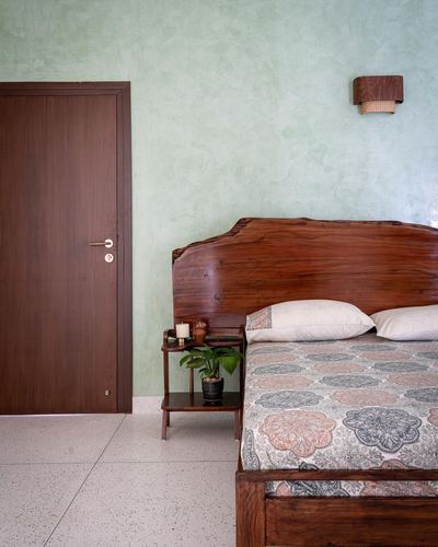 Bedroom with live-edge wood headboard, green textured wall, and wooden door
