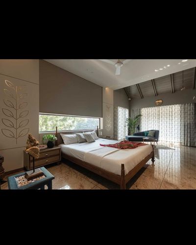 Bedroom with vaulted wood ceiling, wooden bed, carved leaf wall, and glazed garden view