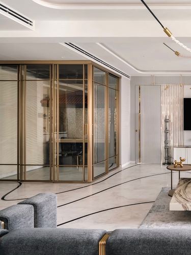 Living area with brass-framed glass partition and curved black-inlaid marble flooring