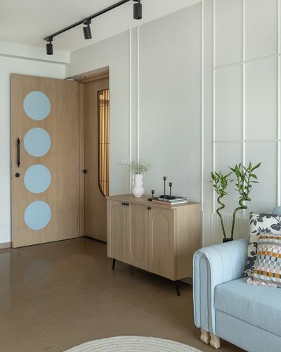 Foyer with sliding wood door with blue circles, arched cabinet, and blue sofa edge