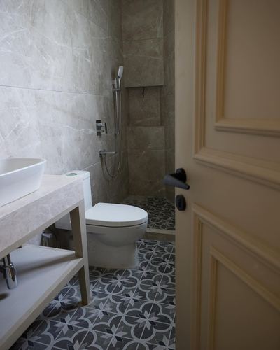 Bathroom with vessel sink, patterned floor tile, and open cream panelled door