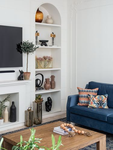 Living room with arched shelving niche, navy sofa, patterned cushions, and wooden coffee table