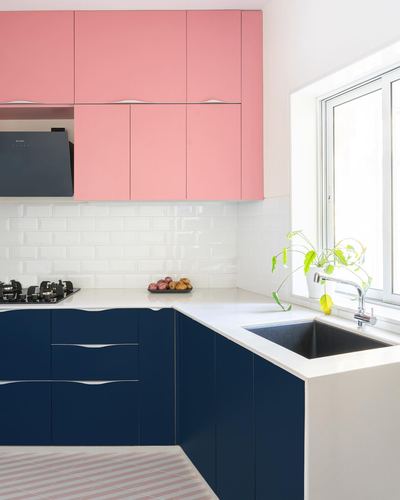 L-shaped kitchen with pink upper cabinets, navy lower cabinets, white subway tile backsplash and window over sink