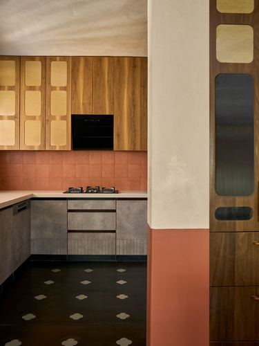 Kitchen corner with cane-inset wood cabinetry, terracotta tile backsplash and patterned stone floor