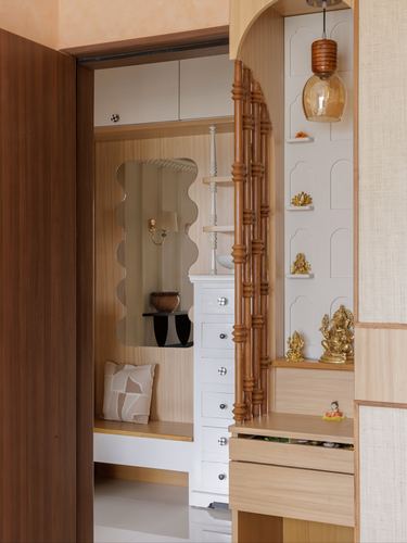 Foyer passage with a turned wood screen opening to an arched pooja niche and dressing area