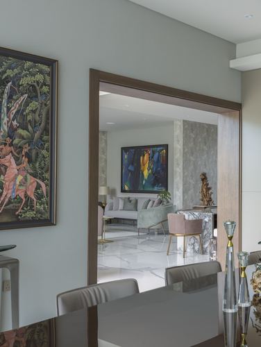 View through a wood-framed doorway into a styled living room with marble floor and art