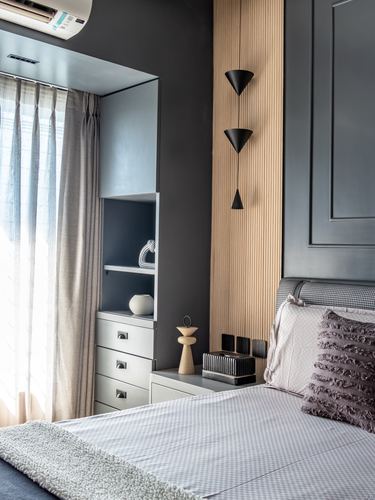 Bedroom corner with fluted wood panel, cascading cone pendant lights, and quilted headboard