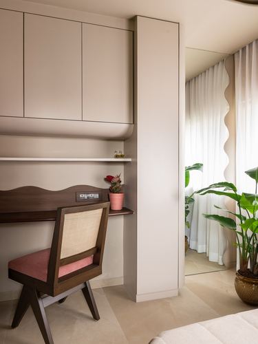 Built-in wooden study nook with cane chair beside a wavy mirror and window with plants