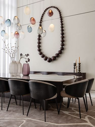 Dining room with marble table, dark wood chairs, and giant bead sculpture on wall