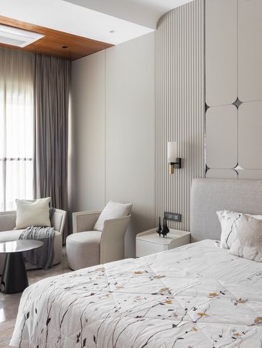 Neutral bedroom with fluted panel wall, upholstered headboard, and floral patterned bedspread