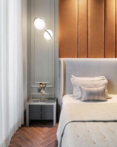 Bedroom corner with amber tufted panel wall, grey upholstered headboard, and twin globe pendant lights