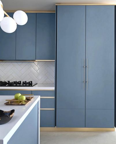 Blue cabinetry kitchen with herringbone tile backsplash, brass accents and globe pendant lights