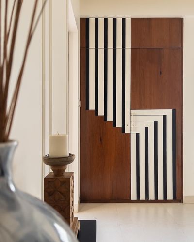 Wood wardrobe with black and white striped geometric pattern, foreground vase and candle