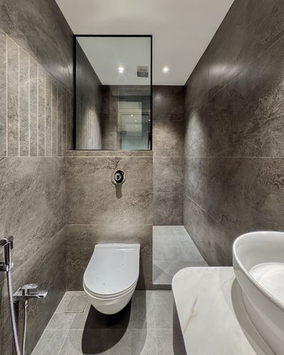Dark stone-clad bathroom with wall-hung toilet, mirror, and marble vessel basin counter