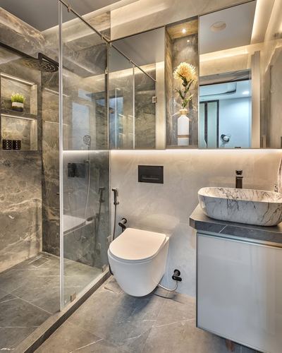 Marble bathroom with glass shower, wall-hung toilet and vessel sink under backlit mirror