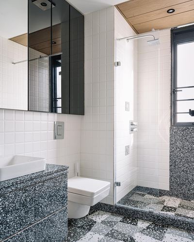 Modern bathroom with square white tile, terrazzo floor and vanity, glass shower and wood ceiling