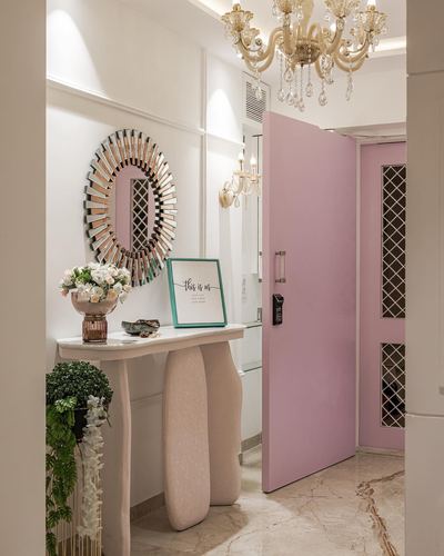 Entry foyer with sunburst mirror, console table, and pink door under a crystal chandelier