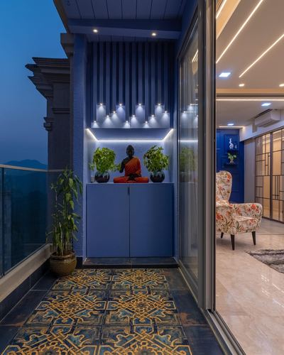Blue-lit balcony niche with Buddha statue, patterned tile floor, view into living room at dusk