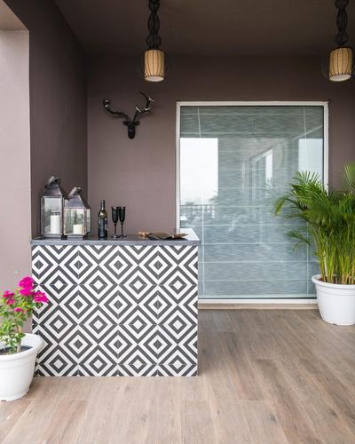 Balcony bar counter with black and white geometric tile, lanterns, and faux antlers on dark wall