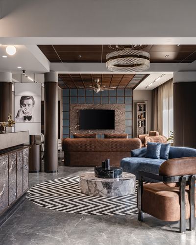Living room with chevron rug, marble drum table, brown and blue sofas facing a stone-clad TV wall