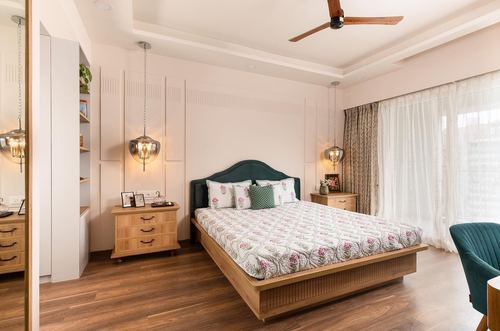 Bedroom with teal upholstered headboard, wooden nightstands, pendant lights and wooden flooring